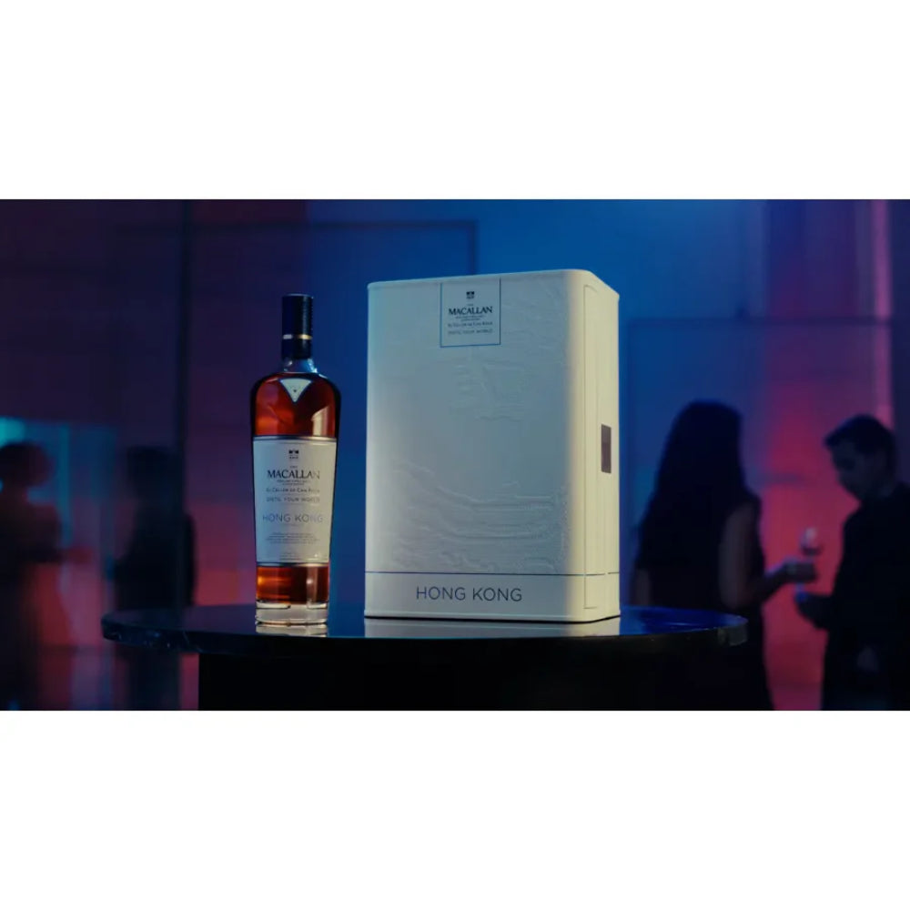 Bottle and box of Macallan whisky with people in the background